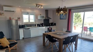 A modern kitchen with a dining area, featuring a large table and chairs, a built-in oven, and a microwave. - BETWEEN LAKES AND MOUNTAINS - DETACHED HOUSE AIR-CONDITIONED 3-BEDROOM WITH ENCLOSED GROUNDS (Barésia-sur-l'Ain)