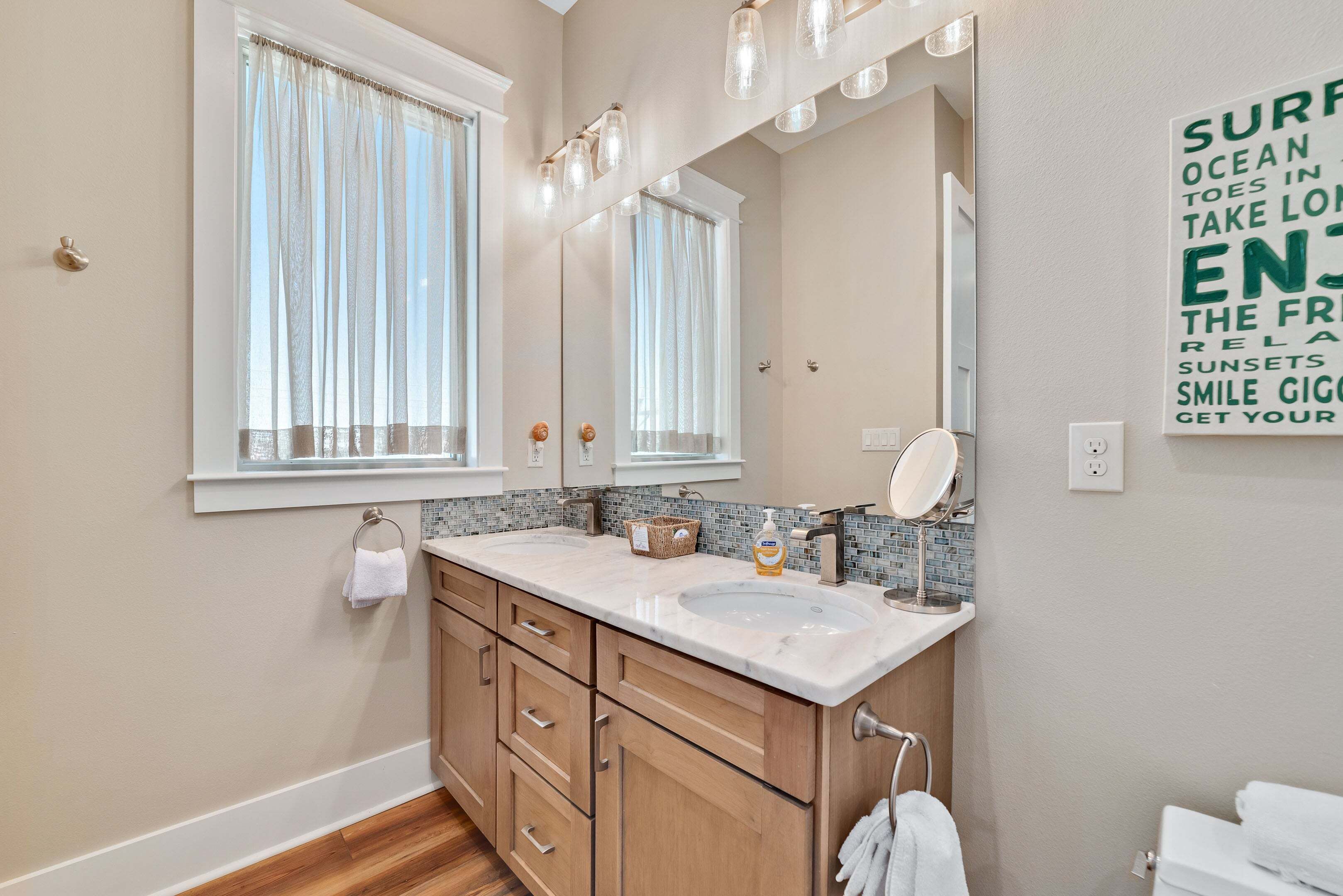 A bathroom with a double sink, wooden cabinets, a large mirror, and a towel rack.