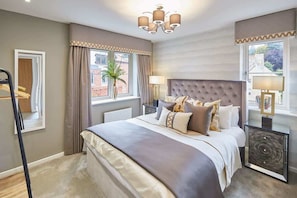 Quarto com uma cama grande, mesa de cabeceira, abajur e janela com cortinas.