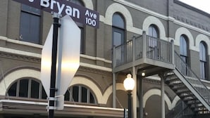 A building with a street sign reading "Bryan Ave 100" and a staircase leading to an upper level.