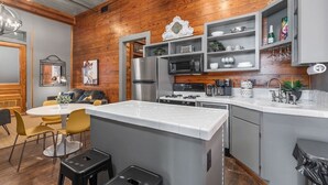 A modern kitchen with a central island, built-in appliances, and a dining area with yellow chairs.