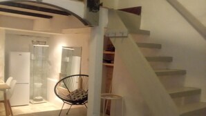 A modern interior with a staircase, a round rug, and a chair. - "LE Temps Suspendu"studio de Charme3,filet de Détente Suspendu (Malaucène)
