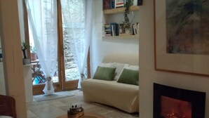 A cozy living room with a fireplace, a sofa, a coffee table, and a bookshelf. - "LE Temps Suspendu"studio de Charme3,filet de Détente Suspendu (Malaucène)