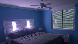 A bedroom with a bed, a nightstand, a ceiling fan, and a window with blinds. - PR-PARADISE, Serenity-3-BEDROOM-2 BathRM- APT -PARKING, POOL-WiFI-close to BEACH (Rio Grande)