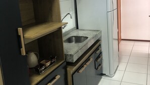 A modern kitchen with dark cabinetry, a granite countertop, and a built-in sink. - Apartment in Ponta Verde, 3 blocks from the beach. (AL)