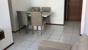 A dining area with a table and chairs, a chandelier, and a wooden door. - Apartment in Ponta Verde, 3 blocks from the beach. (AL)