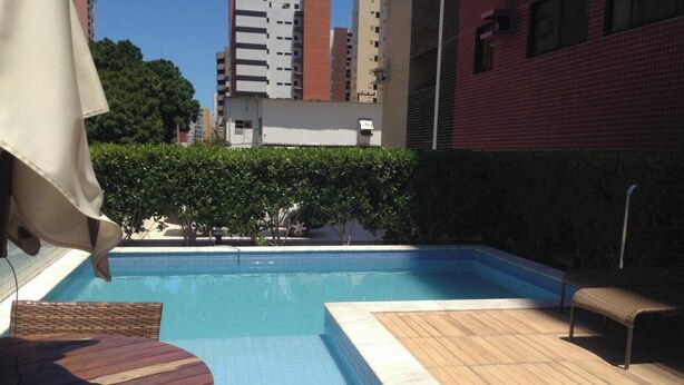 A swimming pool with a wooden deck and a table. - Apartment in Ponta Verde, 3 blocks from the beach. (AL)