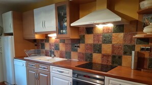 Een keuken met een betegelde spatwand, roestvrijstalen apparatuur en houten kastjes.
