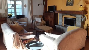 Een gezellige woonkamer met een open haard, comfortabele zitplaatsen en uitzicht op de omgeving.