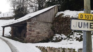 Een landweg met een stenen gebouw en een bord waarop 