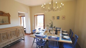 A dining area with a wooden table set for six, blue chairs, and a chandelier. - Chianti Tuscany: a villa with a view (Lucolena)