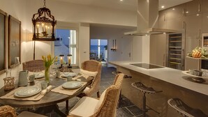 Una cucina moderna con zona pranzo, che include un tavolo rotondo, sedie in vimini e una lampada a sospensione.