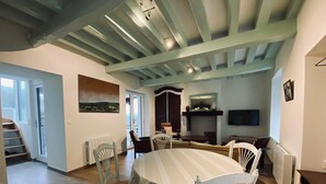 A dining area with a round table, white chairs, and a view of the outdoors through a sliding door. - Impressionist artist's house on the GR2 (La Roche-Guyon)