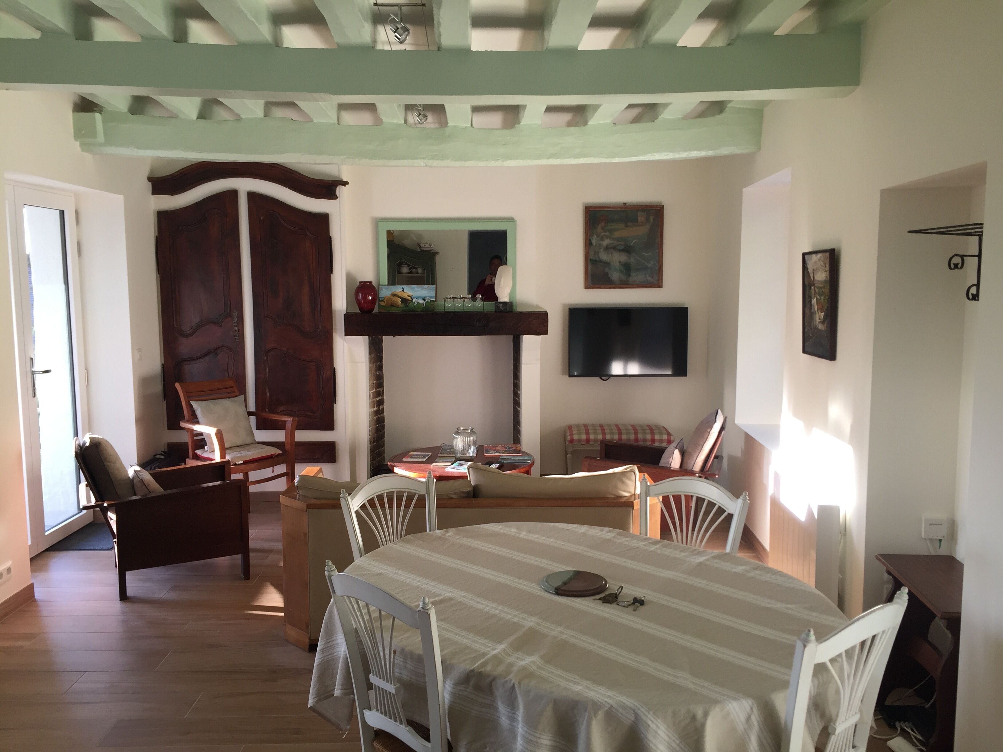 Una habitación con una mesa de comedor, sillas, un televisor y una puerta de madera.