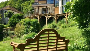 A wooden bench in a lush garden with a house in the background. - Impressionist artist's house on the GR2 (La Roche-Guyon)