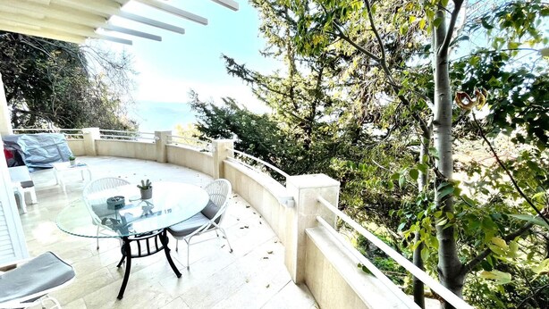 A patio with a round table and chairs, a covered seating area, and a view of the sea. - Broummana House (Broumana)