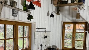 A kitchen with wooden cabinets, a hanging light fixture, and a window with a view of greenery. - LE CAFÉ SALON bei der Weinstraße 20Min von Straßburg. (Rangen)
