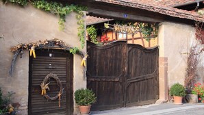 A rustic building with a wooden door, a wreath, and potted plants. - LE CAFÉ SALON bei der Weinstraße 20Min von Straßburg. (Rangen)