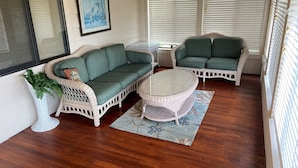 A cozy room with wicker furniture, a round table, and a large window with blinds. - Former Hunting Lodge on 24 Acres with Lake with heated pool (Spring Hill)
