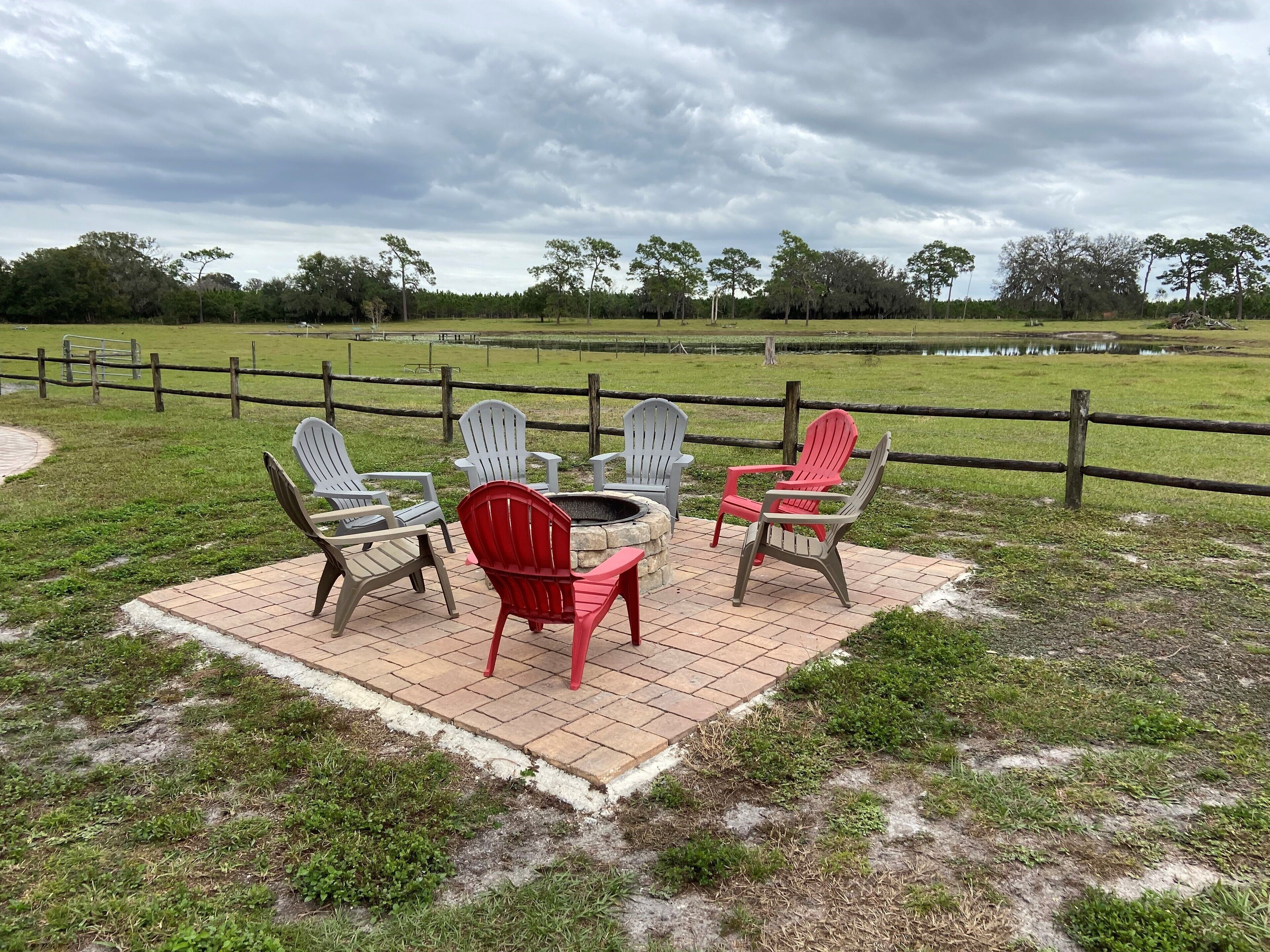 Eine Terrasse mit Adirondack-Stühlen und einem Feuerkorb.