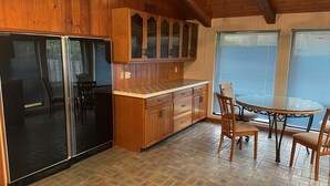 A kitchen with wooden cabinets, a black refrigerator, a dining table with chairs, and a window with blinds. - Former Hunting Lodge on 24 Acres with Lake with heated pool (Spring Hill)
