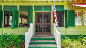 A building with a green facade, a front door with glass panels, and an American flag. - Amazing Porches, Steps From Seaside, FL Beach! One Story + 2 Adult Bikes! (Santa Rosa Beach)
