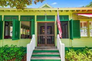 A building with a green facade, a front door with glass panels, and an American flag. - Amazing Porches, Steps From Seaside, FL Beach! One Story + 2 Adult Bikes! (Santa Rosa Beach)