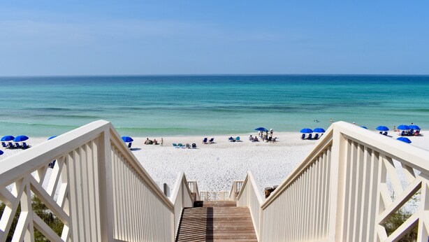 A wooden staircase leading to a beach with white sand and blue umbrellas. - Amazing Porches, Steps From Seaside, FL Beach! One Story + 2 Adult Bikes! (Santa Rosa Beach)