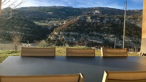 Mesa y sillas colocadas al aire libre con vistas a un paisaje montañoso.