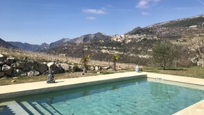 Una piscina cristalina con vistas a montañas y una estatua de Buda de piedra.