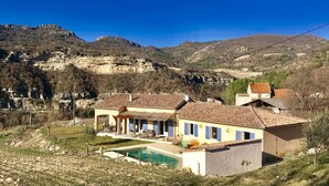 Una casa de dos pisos con piscina, rodeada por un paisaje montañoso.