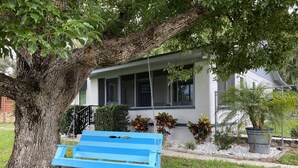 Ein Haus mit Veranda, Schaukel und Baum.