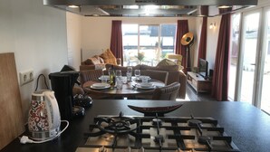Eine moderne Küche mit Gasherd, Wasserkocher und Essbereich mit einer Couch und Tisch für zwei Personen.