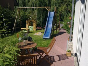 A backyard with a slide, playhouse, and outdoor seating area. - Leipzig oasis, bright and quiet with terrace/barbecue,15min city, 15min lake /Belantis (Leipzig)