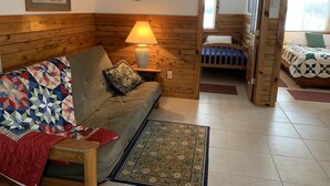 Une pièce chaleureuse avec une tête de lit en bois, un canapé matelassé, une lampe, un tapis et un lit recouvert d’une couvre-lit à motifs.