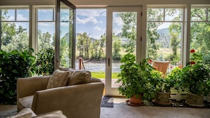 A room with a sofa, potted plants, and a view through large glass doors. - River Frontage! Family Friendly Mtn Retreat (Glenwood Springs)
