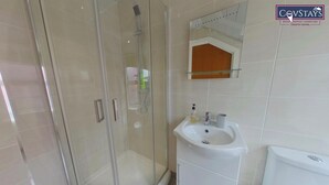 A bathroom with a glass-enclosed shower, a white sink, and a toilet. - Victoria House - Deluxe Studio by CovStays (Coventry)