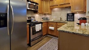 A modern kitchen with wooden cabinets, stainless steel appliances, and a granite countertop. - Townhome in gated community nearby a lot of attraction shopping and restaurants  (Sandy Springs)