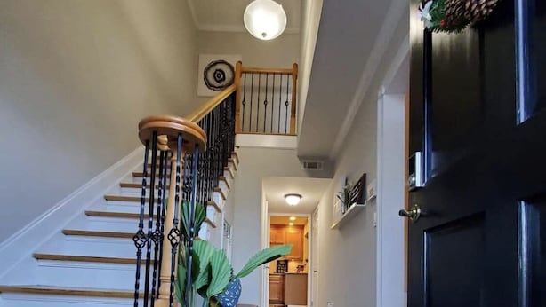 A staircase with wooden steps and black railings, leading to a landing with a bench and a potted plant. - Townhome in gated community nearby a lot of attraction shopping and restaurants  (Sandy Springs)