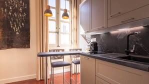 A modern kitchen with a black countertop, stainless steel sink, and a coffee machine. There are two pendant lights above the counter and a window with curtains. - La Suite N°3 Appt n°IV Charming historic center of Avignon (Avignon)