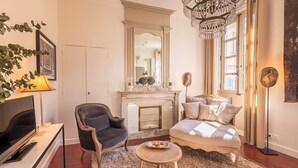 A cozy living room with a fireplace, a sofa, a chair, a TV, and a chandelier. - La Suite N°3 Appt n°IV Charming historic center of Avignon (Avignon)