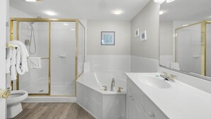 Ein modernes Badezimmer mit begehbarer Dusche, einer Badewanne und einem großzügigen Waschtisch mit Spiegel.