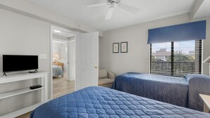 Ein Schlafzimmer mit zwei Betten, einem Fernseher und einem Deckenventilator.