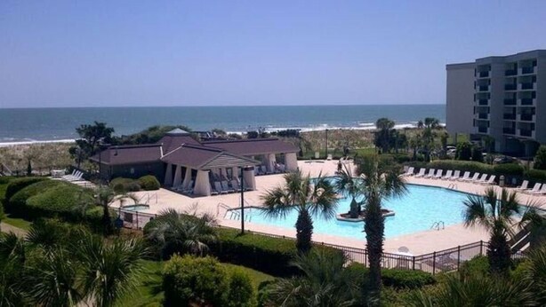 Ein Resort mit Pool, Palmen und Blick auf den Ozean.