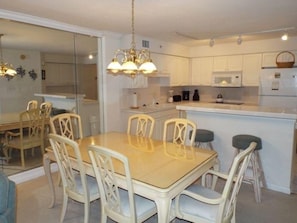 Une cuisine moderne avec des meubles blancs, un îlot central et un coin repas comprenant une table et des chaises.