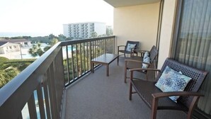 Ein Balkon mit Blick auf ein Gebäude und einen Pool. Zwei Stühle und ein Tisch sind vorhanden.
