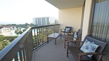 Un balcón con vistas a un edificio y una piscina. Hay dos sillas y una mesa.