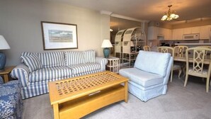 Ein Wohnzimmer mit gestreifter Couchgarnitur, einem Holztisch und einem Essbereich mit einer Chandelier.
