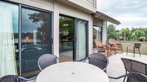 Un patio exterior moderno con una mesa redonda, sillas de mimbre, puertas de vidrio correderas grandes y vistas del entorno.