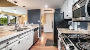 Una cocina moderna con estufa integrada, refrigerador y amplio espacio en las encimeras.